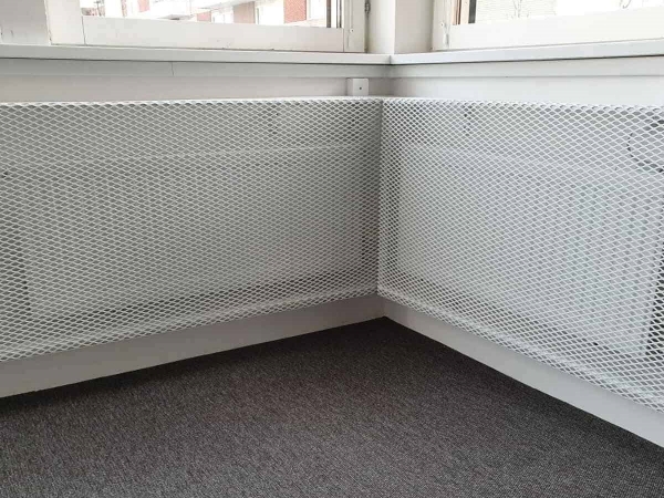 白色的钢板网网罩安装在室内暖气设备上。